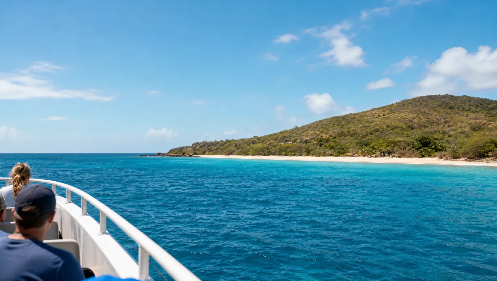 Over the rail on the way across: a low green island and a pale strip of sand ahead